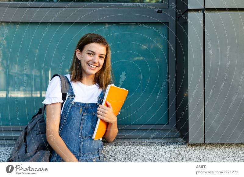 Porträt einer glücklichen Schülerin, die sich an das Fenster der Schule lehnt Lifestyle Glück schön Studium Frau Erwachsene Jugendliche brünett Lächeln lachen