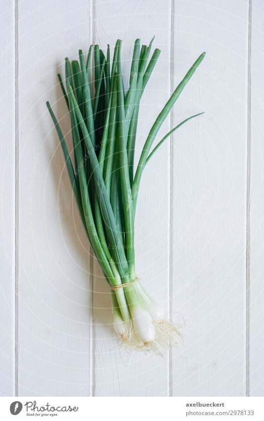 Bund Frühlingszwiebeln Lebensmittel Gemüse Ernährung Vegetarische Ernährung Gesunde Ernährung frisch Essen zubereiten Küchentisch Tisch Holztisch Holzbrett