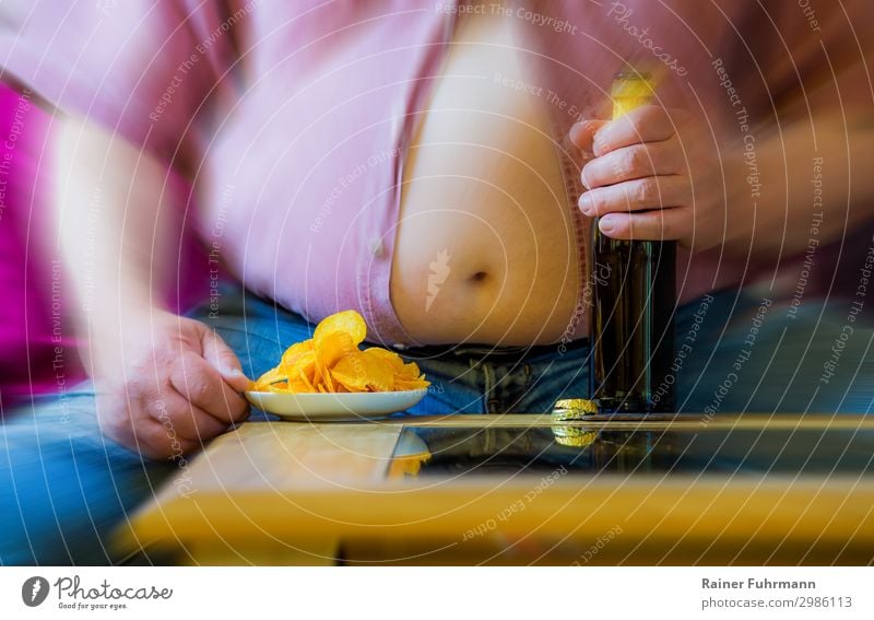 Ein Mann mit dickem Bauch sitzt an einem Tisch. Auf dem Tisch stehen Bier und Kartoffelchips. Mensch maskulin Erwachsene Männlicher Senior 1 Hemd Jeanshose