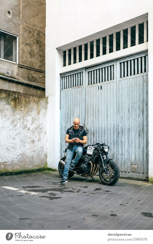 Biker suchen mobiles Sitzen auf dem Motorrad Lifestyle Stil Ausflug PDA Mensch Mann Erwachsene Straße Fahrzeug sitzen warten authentisch retro schwarz