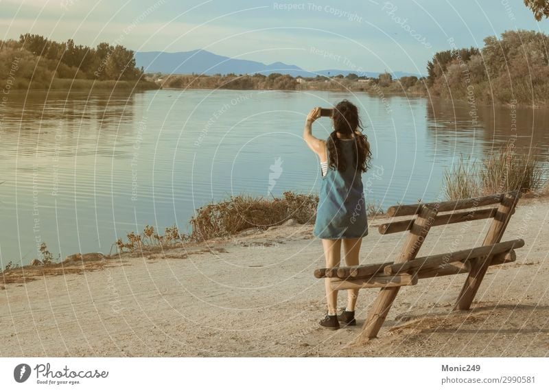 Brünette Frau, die mit einem Handy einen Fluss fotografiert. Erholung Modellbau Ferien & Urlaub & Reisen Abenteuer Sommer Sommerurlaub Berge u. Gebirge sprechen