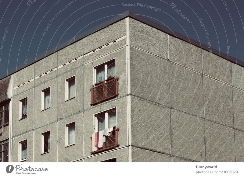 Obere graue Fassade eines Hochhauses, vor einem blauen Himmel, mit Fenstern und Wäsche zum trocknen Stadt Haus Bauwerk Gebäude Architektur Mehrfamilienhaus