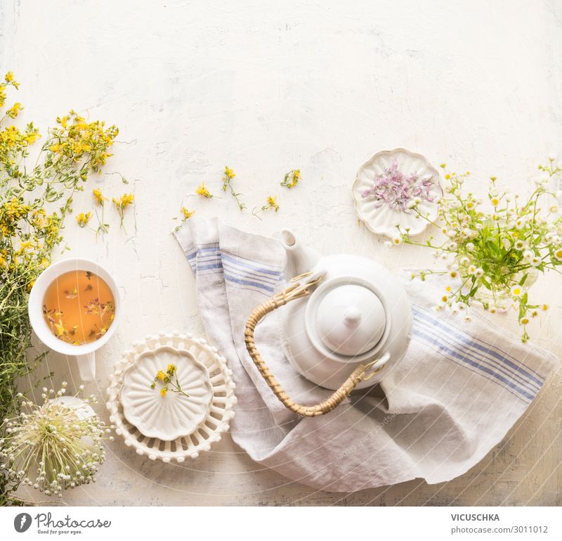 Kräuterteeset mit frischen Heilkräutern, Teekanne und Tasse Tee. Johanniskrautkräuter und Blumen auf weißem Tischhintergrund, Ansicht von oben. Kräutermedizin. Natürliches Nahrungsergänzungsmittel