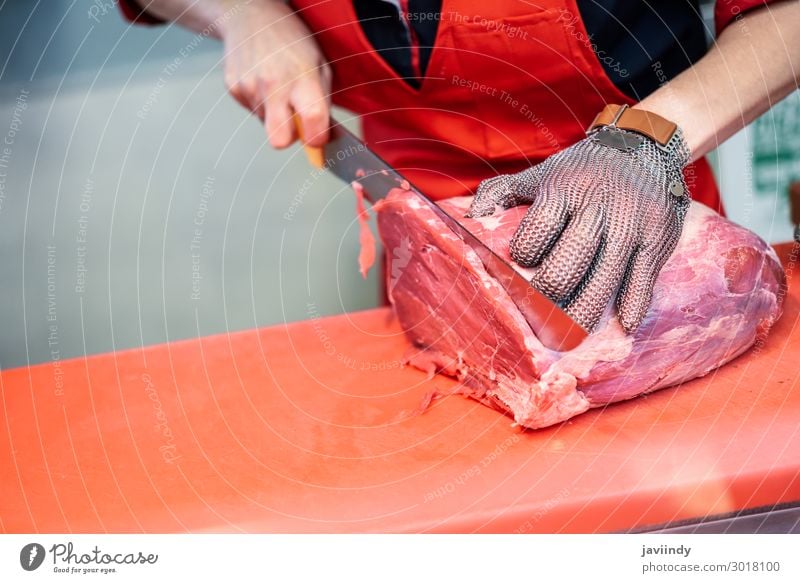 Metzgerin beim Schneiden von Frischfleisch in einer Metzgerei mit Metallschutzhandschuh Lebensmittel Fleisch kaufen Arbeit & Erwerbstätigkeit Beruf Business