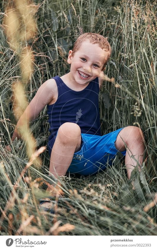 Kleine glückliche lächelnde Kinder, die in einem hohen Gras spielen. Lifestyle Freude Glück Erholung Ferien & Urlaub & Reisen Sommer Sommerurlaub Mensch Junge 1