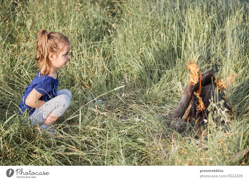 Kleines Mädchen, das am Lagerfeuer steht und in einem Gras sitzt. Lifestyle Freude Glück Erholung Ferien & Urlaub & Reisen Sommer Sommerurlaub Kind Mensch Frau