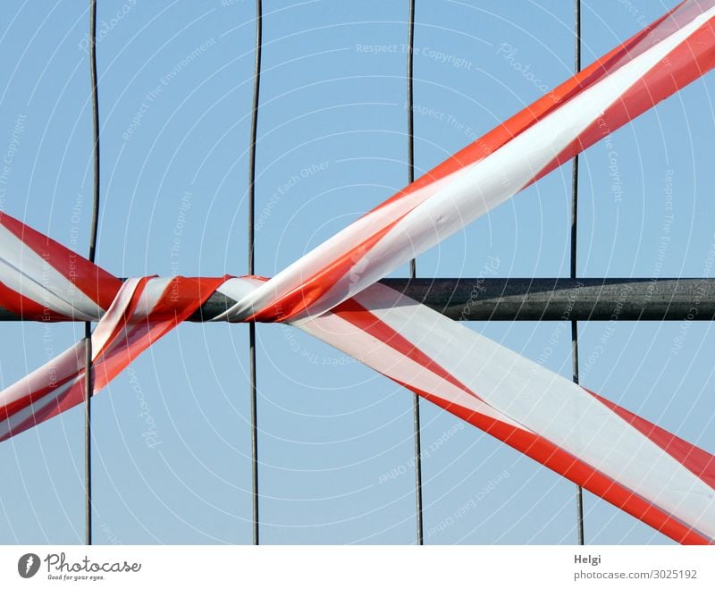 rot-weißes Absperrband an einem Zaun Wolkenloser Himmel Absperrgitter Barriere Metall Kunststoff Linie Schnur festhalten stehen authentisch außergewöhnlich