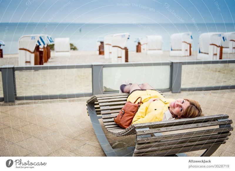 junge Frau im gelben Regenmantel liegt auf Strandliege Deutschland Ostsee Timmendorfer Strand Meer Wasser Küste maritim Ferien & Urlaub & Reisen Horizont