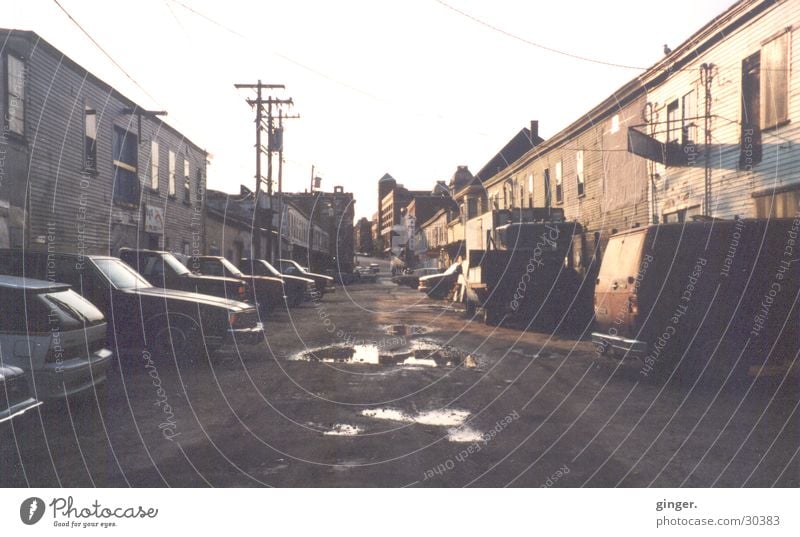 Seitenstraße Straße trist Maine Pfütze Hochspannungsleitung Haus Häuserzeile Schlagloch Ghetto analog Menschenleer Zentralperspektive schäbig Tag verfallen