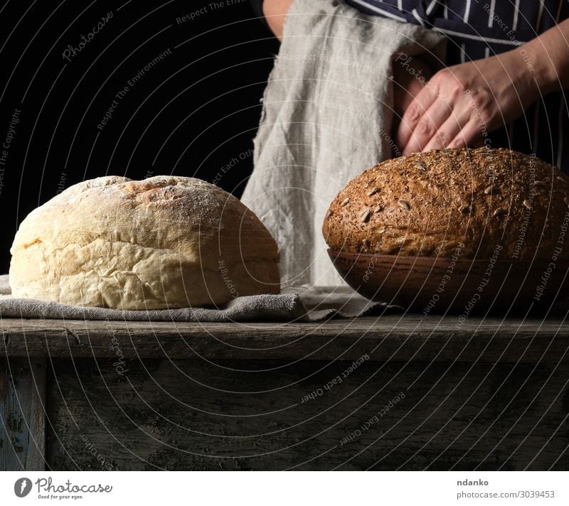 gebackenes Rundbrot auf einem Holztisch Brot Teller Tisch Küche Mensch Frau Erwachsene Arme Hand alt machen frisch braun gelb grau schwarz weiß Tradition