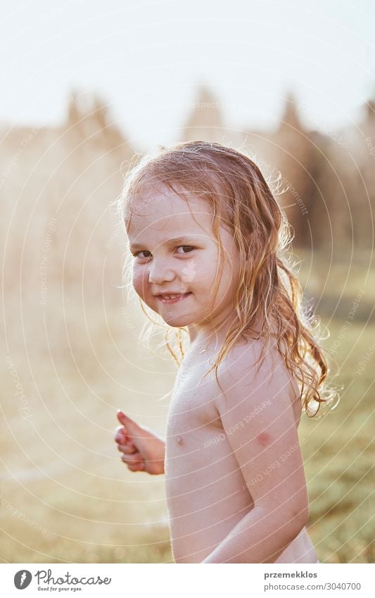 Kleine niedliche adorable Mädchen genießen ein kühles Wasser von ihrer Mutter während heißen Sommertag im Hinterhof gesprüht. Unverfälschte Menschen, echte Momente, authentische Situationen