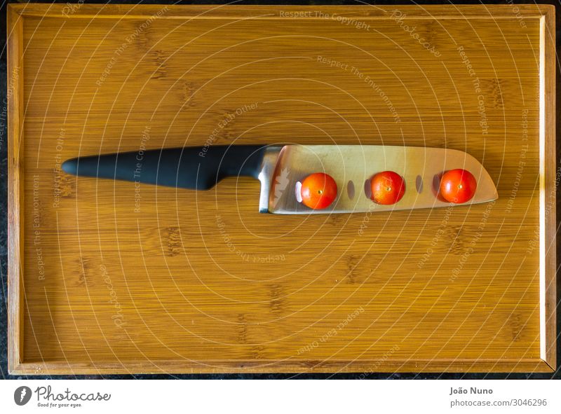 Balancieren von Kirschtomaten über dem Kochmesser Gemüse Salat Salatbeilage Ernährung Mittagessen Abendessen Bioprodukte Vegetarische Ernährung Diät Besteck