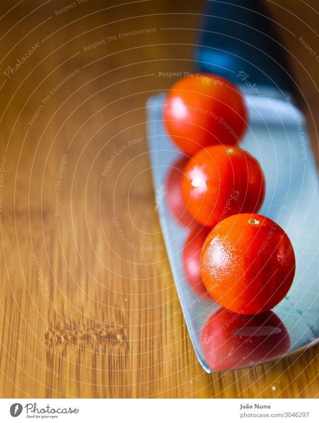 Kirschtomaten über einem Kochmesser Gemüse Ernährung Mittagessen Bioprodukte Vegetarische Ernährung Diät Besteck Messer Metall Stahl Gleichgewicht Küchenchef