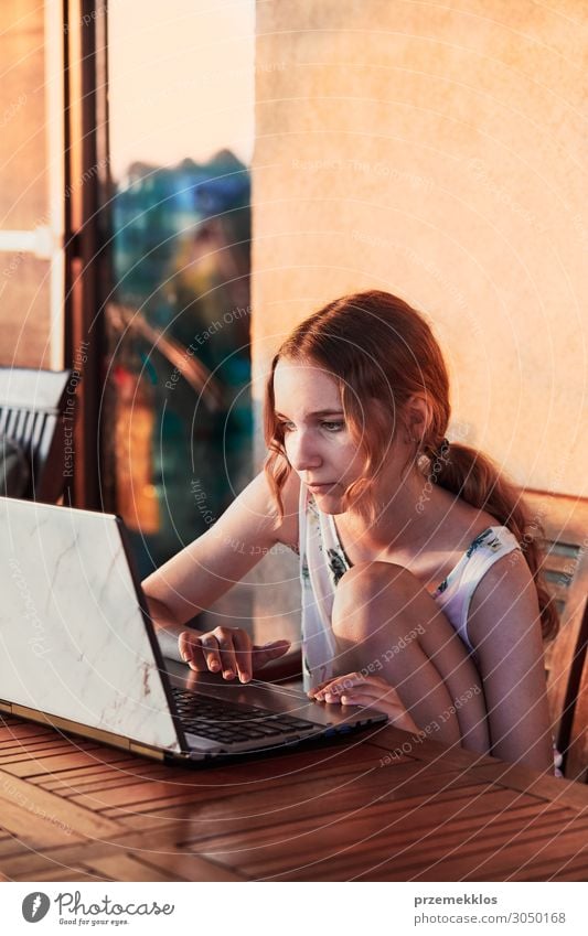 Frau bei der Arbeit zu Hause, mit tragbarem Computer, sitzt auf der Terrasse an einem Sommertag Garten Schreibtisch Tisch Schule lernen