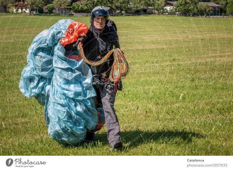 Mit Schirm, Charme und Melone |  Nach dem Gleitschirmfliegen Freizeit & Hobby maskulin 1 Mensch Sommer Baum Gras Wiese Dorf Haus Jeanshose Helm Paraglideschirm