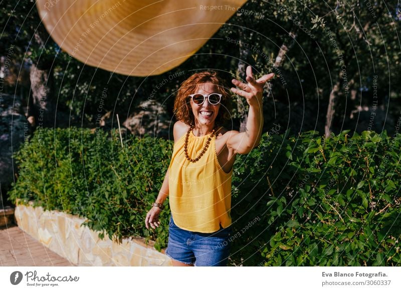 Hübsches Mädchen bei Sonnenuntergang, das einen Hut in der Hand hält und ihn in die Kamera wirft. Sommer, Spaß und Lifestyle im Freien Freiheit Mensch Lächeln