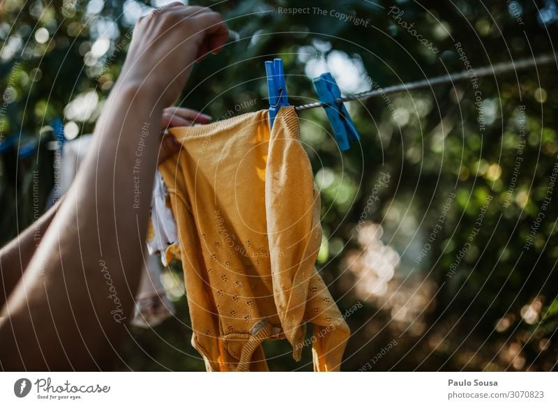 Nahaufnahme einer Frau, die Kleidung an der Linie hängt. Lifestyle Mensch feminin Hand 1 Bekleidung festhalten hängen natürlich Energie Wäscheleine