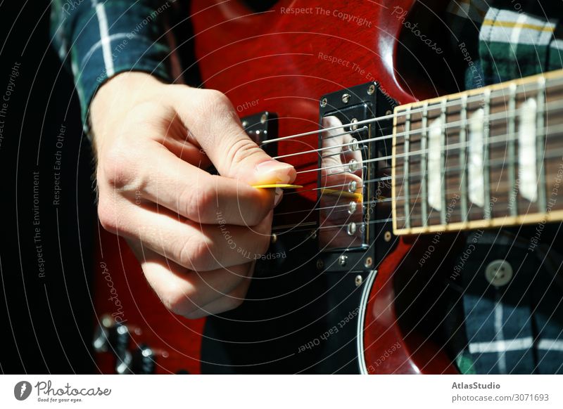 Mann spielt auf E-Gitarre vor dunklem Hintergrund, Nahaufnahme Instrument Lichtschein schließen live pflücken Musiker jung Tisch Raum spielen Blues Gesang solo