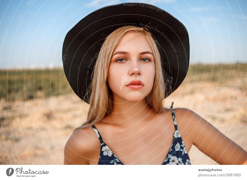 ein Nahaufnahme-Portrait eines blauäugigen blonden Mädchens mit schwarzem Hut Windstille Kleid während expressiv Auge Gesicht Frau geblümt Glamour traumhaft