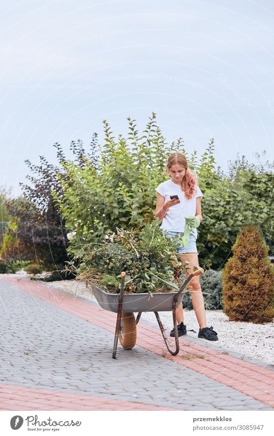 Teenager-Mädchen bei der Arbeit in einem Hausgarten Lifestyle Glück Freizeit & Hobby Sommer Garten Arbeit & Erwerbstätigkeit Gartenarbeit Telefon Handy PDA