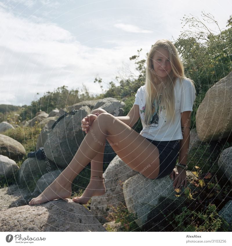 Portrait einer jungen, großen Frau, die auf einer Felsendüne sitzt und lächelt Stil Freude schön Leben Wohlgefühl Sommer Sommerurlaub Strand Junge Frau