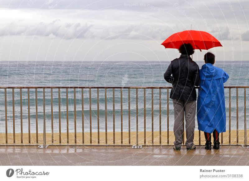 Paar mit Schirm an der Küste bei Barcelona Mensch 45-60 Jahre Erwachsene Wolken Herbst schlechtes Wetter Regen Strand Blick warten Zusammensein Gefühle