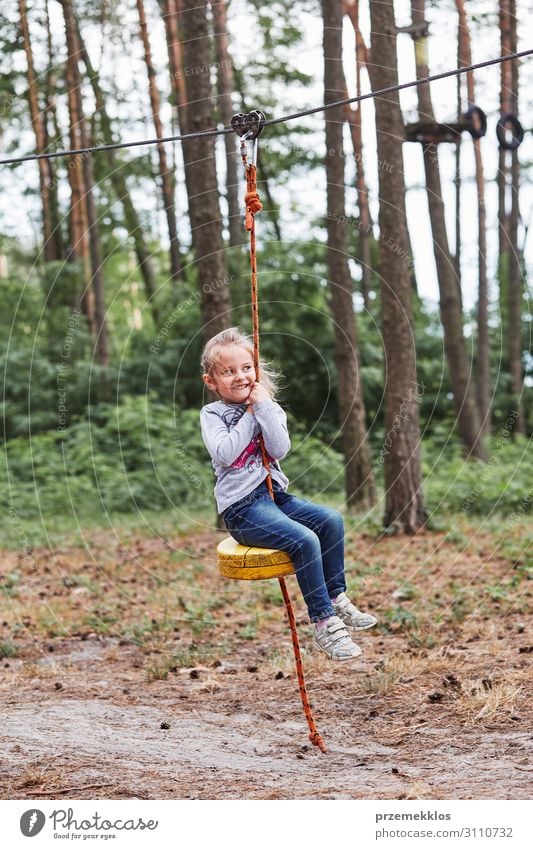 Glückliches Mädchen fährt an der Seilbahn im Seilpark. Freude Spielen Ferien & Urlaub & Reisen Abenteuer Sommer Kind Mensch Kindheit Park Wald Spielplatz Linie