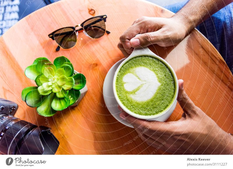 Mann mit Matcha Grüner Tee Latte Kunst auf einem Tisch in einem Café. Lebensmittel Kaffeetrinken Getränk Heißgetränk Latte Macchiato Espresso Tasse Lifestyle