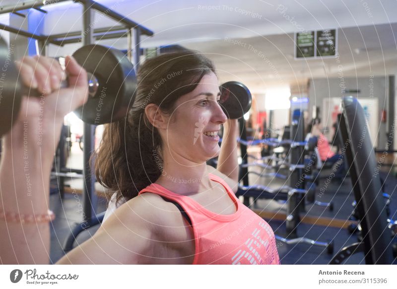 Frau beim Training im Fitnessstudio mit Gewichten Lifestyle Sport Sportler Erwachsene Lächeln muskulös Einsamkeit anstrengen Erwachsene mittleren Alters