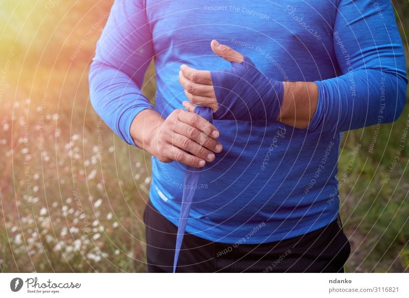 Athlet steht auf und wickelt seine Hände in einen blauen Verband. Lifestyle Körper sportlich Freizeit & Hobby Sommer Sport Mensch maskulin Mann Erwachsene Hand