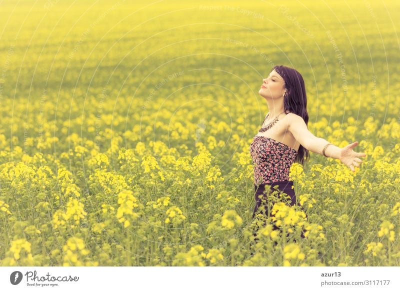 Schöne junge Frau im Sommer auf gelber Wiese aus Raps bis zum Horizont. Hübsches Mädchen mit Lebensfreude geniesst die Sonnenschein Pause und das Leben. Erholung und Energie tanken vom Zeit Stress in der Umwelt und Natur Idylle. Augen geschlossen.