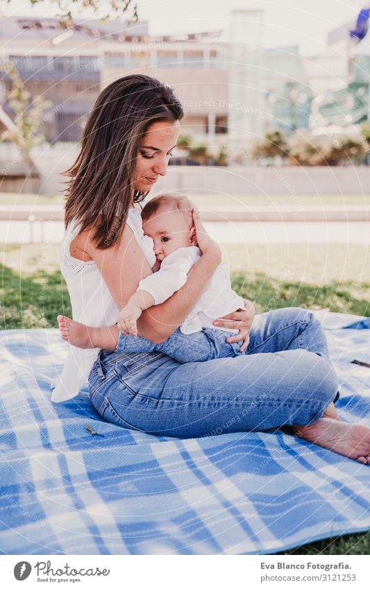 junge Mutter stillen, die ihr kleines Mädchen im Freien in einem Park füttert. Essen Lifestyle Freude schön Sommer Sonne Kindererziehung feminin Baby Junge Frau