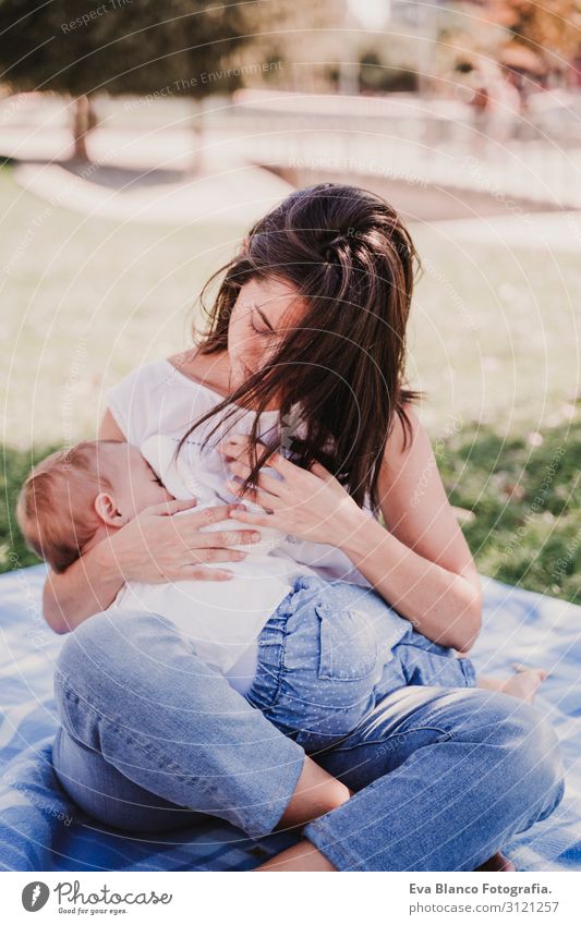 junge Mutter stillen, die ihr kleines Mädchen im Freien in einem Park füttert. Essen Lifestyle Freude schön Sommer Sonne Kindererziehung Mensch feminin Baby