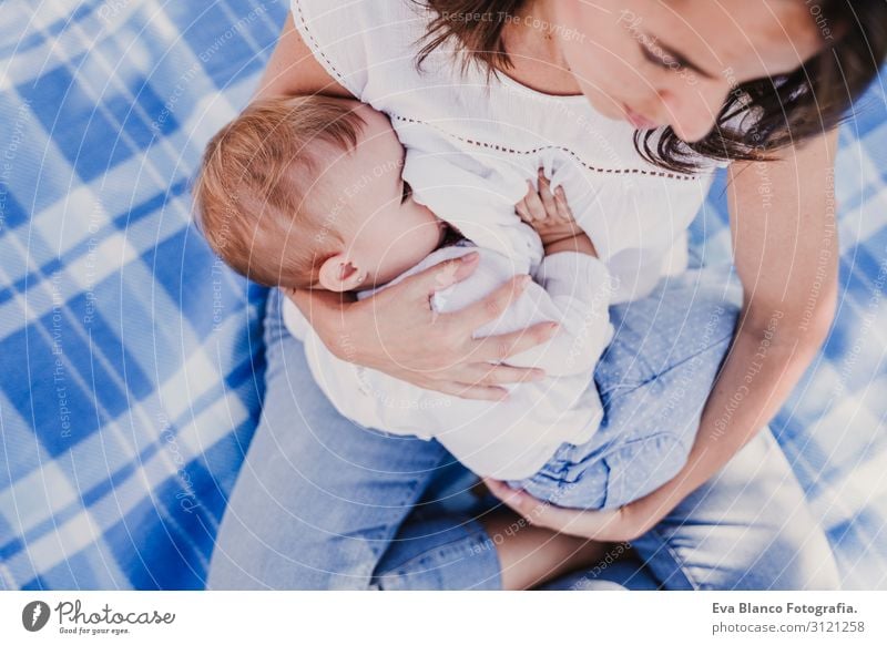 junge Mutter stillen, die ihr kleines Mädchen im Freien in einem Park füttert. Essen Lifestyle Freude schön Sommer Sonne Kindererziehung feminin Baby Junge Frau