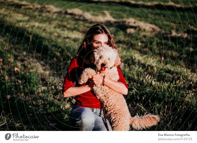 schöne kaukasische Frau mit ihrem süßen braunen Pudelhund bei Sonnenuntergang auf dem Land. Haustiere und Lebensweise im Freien Jugendliche Feld Hut Lifestyle