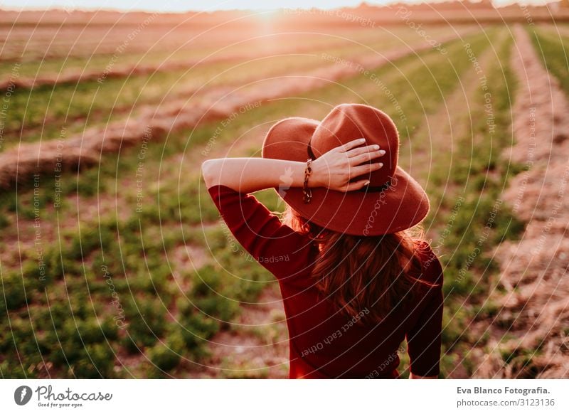 eine schöne weiße Frau, die den Sonnenuntergang auf dem Land beobachtet. Entspannung und Lebensstil im Freien Jugendliche Feld Hut Lifestyle lässig Gegenlicht