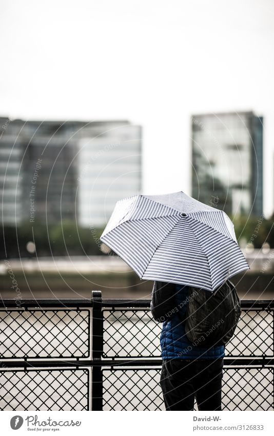 verregnet Mann steht Regenschirm Zaun draußen Herbst herbstlich schlechtes Wetter Häuser Stadt Unwetter nass Wassertropfen Farbfoto Außenaufnahme Rückansicht