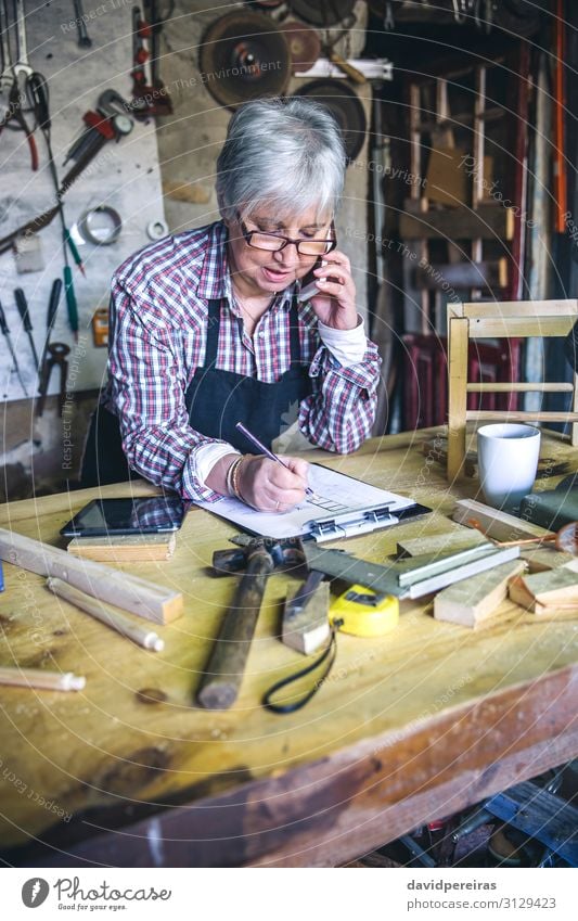 Älterer weiblicher Schreiner am Telefon Handwerk Business sprechen Hammer Mensch Frau Erwachsene Holz alt authentisch Zimmerer Senior Mobile maßgearbeitet