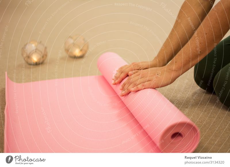 Die Hände der Frau rollen eine rosa Yogamatte auf. Lifestyle Körper Haut Gesundheitswesen Wellness Erholung Meditation Spa Massage Sport Mensch Erwachsene Hand