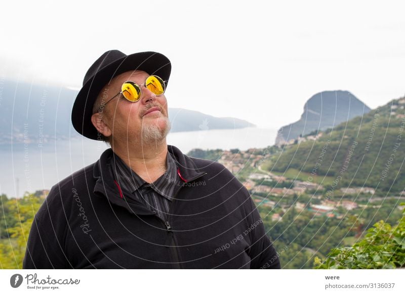 Old man in hat and sunglasses Mensch genießen träumen alt Bearded Granfather Lake Garda Portrait Senior bestager camera caucasian church church tower copy space