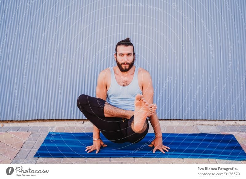 mann in der stadt, der yoga-sport betreibt. blauer hintergrund. gesunde lebensweise Yoga Mann Sport Gesundheit Außenaufnahme Großstadt Blauer Hintergrund