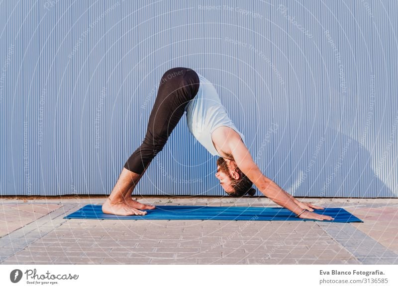 mann in der stadt, der yoga-sport betreibt. blauer hintergrund. gesunde lebensweise Yoga Mann Sport Gesundheit Außenaufnahme Großstadt Blauer Hintergrund