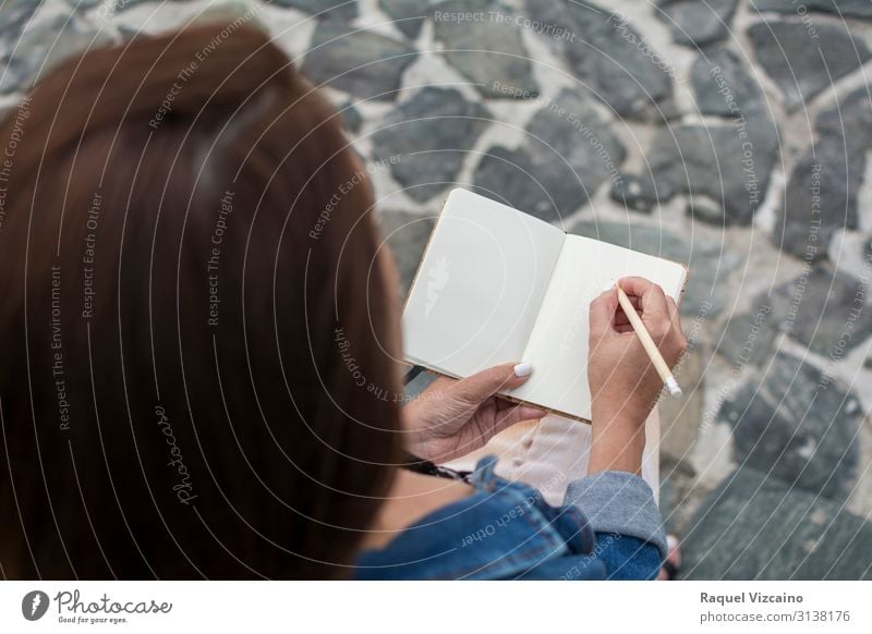 Eine Frau hält ein leeres Notizbuch. Lifestyle lesen Bildung Erwachsenenbildung Mensch 18-30 Jahre Jugendliche Buch schreiben sitzen Beginn Notebook blanko