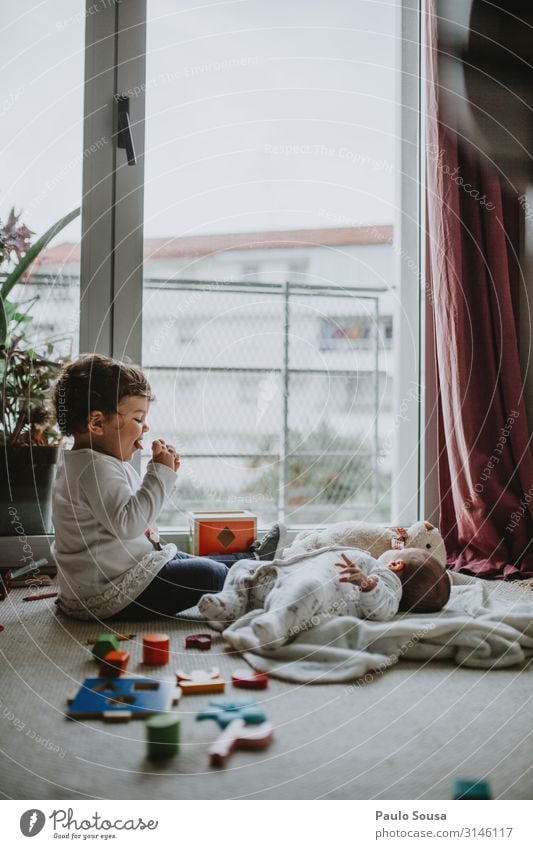 Die Schwester spielt Musik für den kleinen Bruder. Lifestyle Mensch feminin Kind Baby Kleinkind Mädchen Geschwister 2 0-12 Monate 1-3 Jahre entdecken Lächeln