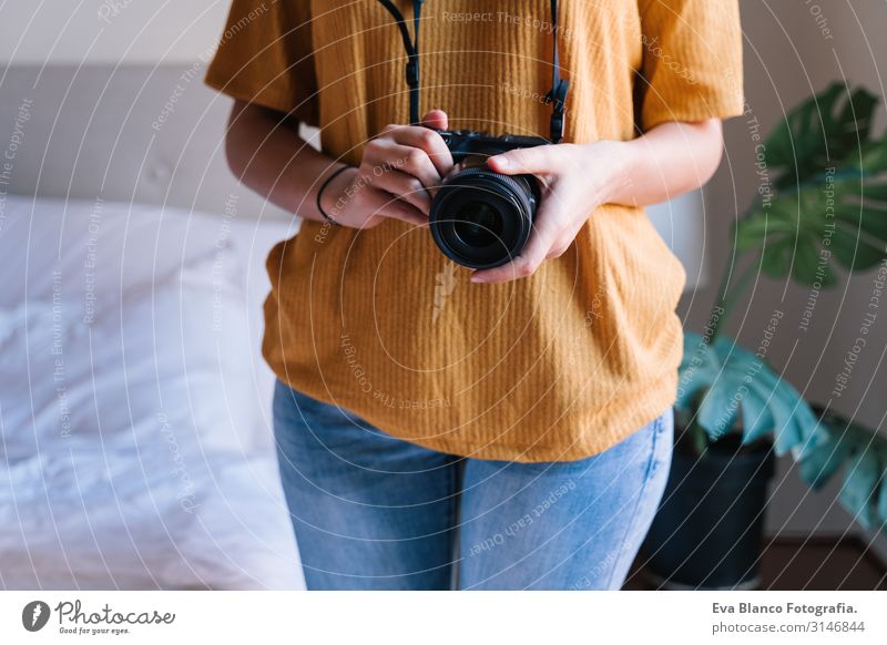 Fotografin zu Hause, die eine Kamera hält. Technologie und Lebensstil in Innenräumen Kaukasier Frau Jugendliche Fotokamera reflektorisch Technik & Technologie