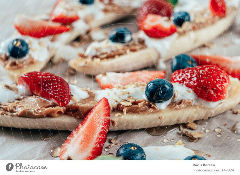 Bananensplit mit Erdbeeren, Heidelbeeren, Mandelbutter und Honig Butter Blaubeeren Split frisch Frucht Hintergrundbild Beeren Sommer Gastronomie Creme Saucen