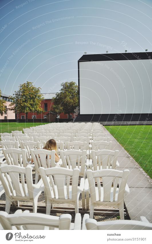 teenager sitzt ganz alleine in einem open-air-kino vor einer großen leinwand Vorstellung Kino Open-Air-Kino Leinwand Platz nehmen sitzen Sitzplatz alles frei