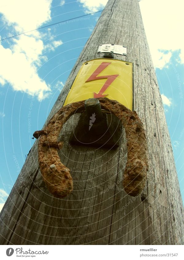 Starkstrom meets Horseshoe Elektrizität Hufeisen Holz Elektrisches Gerät braun Volksglaube Blitze obskur Himmel Strommast Leitung Schilder & Markierungen blau