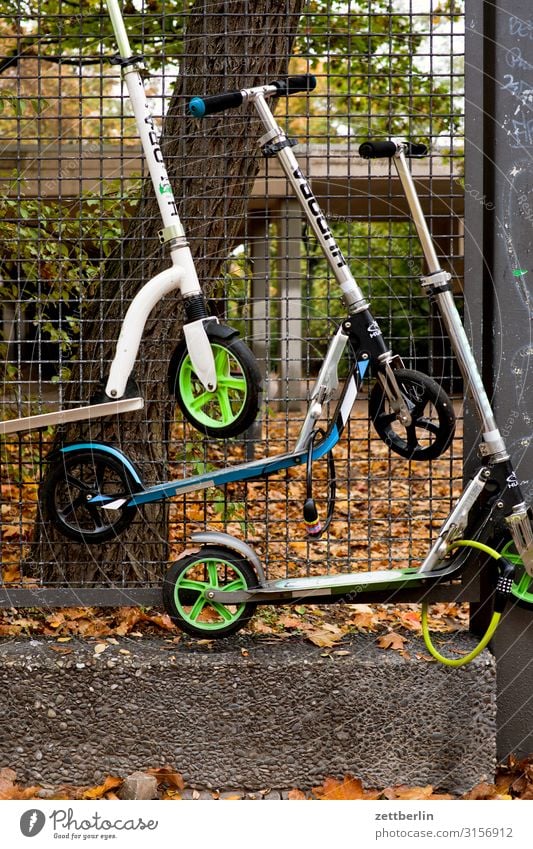 Drei Roller Parkplatz Erholung aufbewahren Grenze Herbst hängen Kindergarten Maschendrahtzaun Menschenleer parken Tretroller Schulgebäude Schulhof Textfreiraum