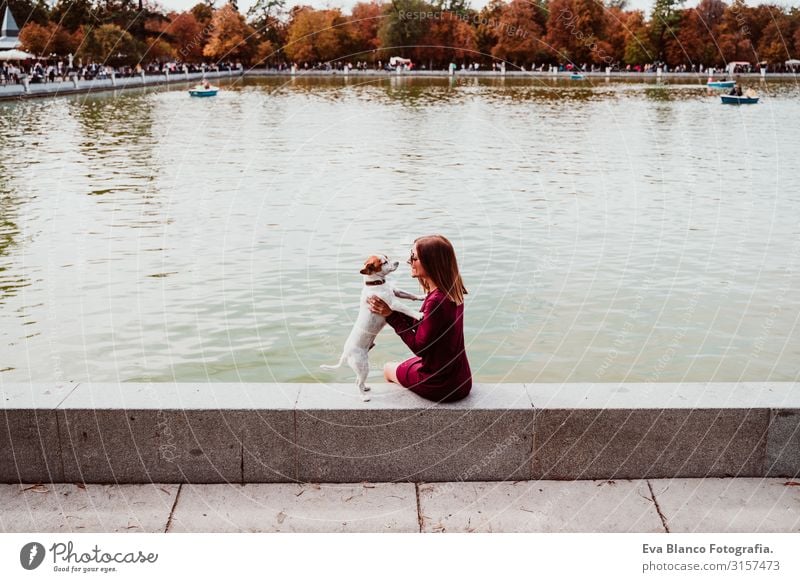 junge Frau und süßer Hund am See in einem städtischen Park. Konzept der Liebe zu Tieren. Retiro-Park Madrid Haustier Außenaufnahme Großstadt Umarmen